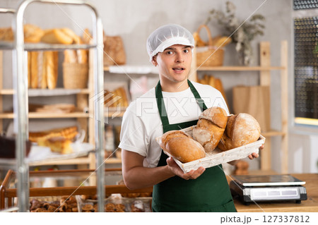 male baker sells croissants, shows off a variety of crescent-shaped buns. male baker sells croissants, shows off a variety of crescent-shaped buns. 127337812