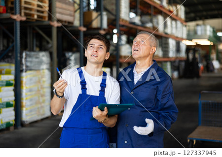 Elderly man and young guy checking documents in warehouse Elderly man and young guy checking documents in warehouse 127337945