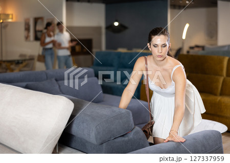 Adult woman chooses sofa in store Adult woman chooses sofa in store 127337959