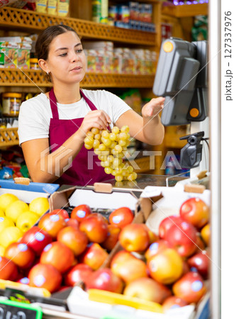 Female shopping assistant weighing grapes in grocery shop 127337976