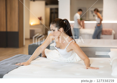 Portrait of attractive woman choosing an orthopedic mattress in home goods store 127338159