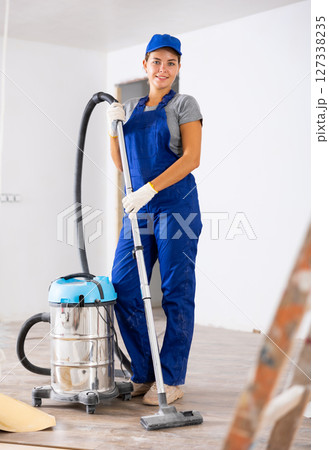 Portrait of a young girl worker with a vacuum cleaner Portrait of a young girl worker with a vacuum cleaner 127338235