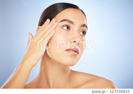 Face, beauty and skincare with model woman in studio on a blue background thinking about natural treatment. Makeup, wellness and aesthetic with an attractive young female posing to promote a product Face, beauty and skincare with model woman in studio on a blue background thinking about natural treatment. Makeup, wellness and aesthetic with an attractive young female posing to promote a product 127338835