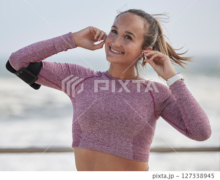 Fitness, woman with earpods for music during run at beach, exercise and training for marathon with podcast or radio streaming. Happy runner, female and listening with workout in nature and wellness Fitness, woman with earpods for music during run at beach, exercise and training for marathon with podcast or radio streaming. Happy runner, female and listening with workout in nature and wellness 127338945