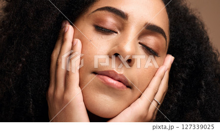 Beauty, face and skincare with a model black woman touching her skin in studio on a brown background. Peace, wellness and relax with an attractive young female posing with her hands on her cheeks Beauty, face and skincare with a model black woman touching her skin in studio on a brown background. Peace, wellness and relax with an attractive young female posing with her hands on her cheeks 127339025