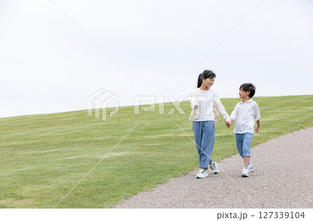 丘の上を笑顔で歩く子ども	 127339104