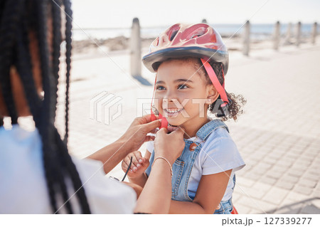 Mother, child and helmet for bicycle, park and help with love, bonding and happiness by ocean in summer. Black woman, child and bike safety for learning, cycling and happy by ocean on family vacation 127339277