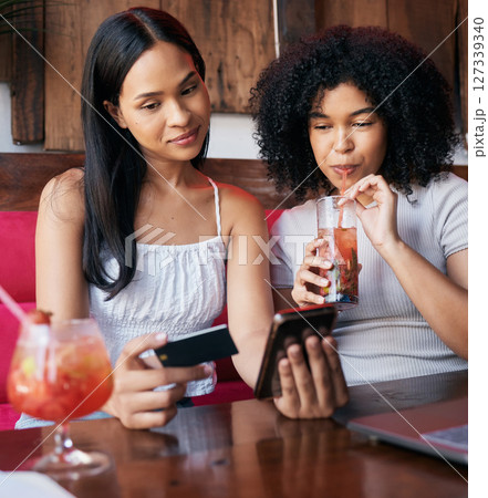 Woman, friends and phone with credit card drinking at restaurant, bar or cafe making online payment or transaction. Women chilling together having a drink in ecommerce or remote banking on smartphone Woman, friends and phone with credit card drinking at restaurant, bar or cafe making online payment or transaction. Women chilling together having a drink in ecommerce or remote banking on smartphone 127339340