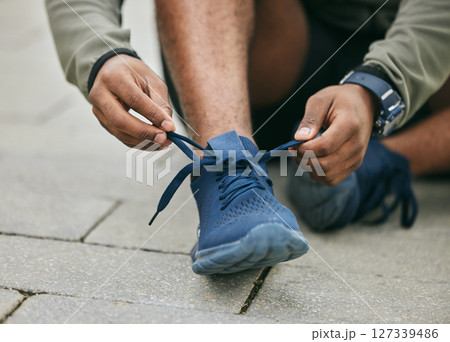 Fitness, hands and black man tie shoes in city and getting ready for running, workout or exercise. Wellness, sports and male runner tying sneaker lace and preparing for training on street outdoors. 127339486
