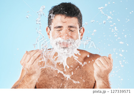Man, shave and water splash for beauty in studio with wellness, health or self care by blue background. Model, cream and water with hands for healthy facial, self love or cosmetics by studio backdrop 127339571