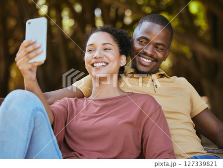 Black couple, phone and selfie with smile at outdoor nature park for travel, happiness and social media profile picture content update. Happy man and woman with 5g network connection on vacation date Black couple, phone and selfie with smile at outdoor nature park for travel, happiness and social media profile picture content update. Happy man and woman with 5g network connection on vacation date 127339821