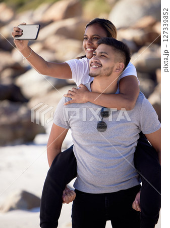 Beach, selfie and piggy back couple, smile with smartphone on romantic summer holiday at ocean. Romance, man and woman at with phone, love and vacation time for happy couple together in Australia. 127339852