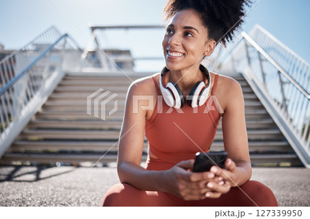 Fitness, headphones and smartphone with woman on stairs thinking of workout, exercise or training website, blog or social media. Mental health technology, sports music and happy black woman in city 127339950