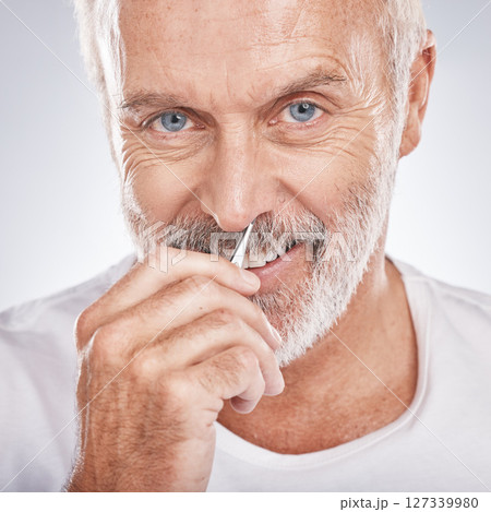 Portrait, tweezers and nose with a senior man in studio on a gray background for grooming or personal hygiene. Face, hand and equioment with a mature male tweezing to remove nasal hair in a bathroom 127339980