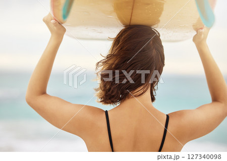 Surfing, beach and woman with a surfboard on her head while on a summer vacation in Hawaii. Travel, freedom and girl on a seaside holiday, trip or adventure in nature outdoor by the ocean to surf. 127340098