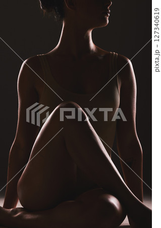 Beauty, body and silhouette of a woman in a studio with a creative, mysterious and seductive aesthetic. Art, fantasy and shadow figure of a female model with a sexy pose by a dark black background. Beauty, body and silhouette of a woman in a studio with a creative, mysterious and seductive aesthetic. Art, fantasy and shadow figure of a female model with a sexy pose by a dark black background. 127340619