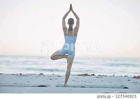 Yoga, fitness and woman doing beach workout for balance, freedom and mindfulness in morning with tree pose for health and wellness. Back of female doing pilates, chakra and zen training at sea 127340923