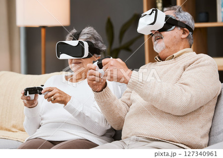 Virtual reality, gaming and senior couple on sofa in living room having fun. Vr gamer, metaverse and retired elderly man and woman playing futuristic, 3d and ai games with controller while relaxing. Virtual reality, gaming and senior couple on sofa in living room having fun. Vr gamer, metaverse and retired elderly man and woman playing futuristic, 3d and ai games with controller while relaxing. 127340961