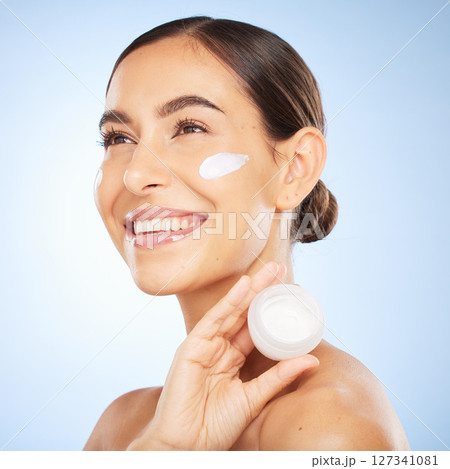 Woman, beauty and face with cream product for happiness vision, skincare wellness or cosmetics dermatology in blue background. Facial care mockup, luxury sunscreen and salon spa treatment in studio 127341081