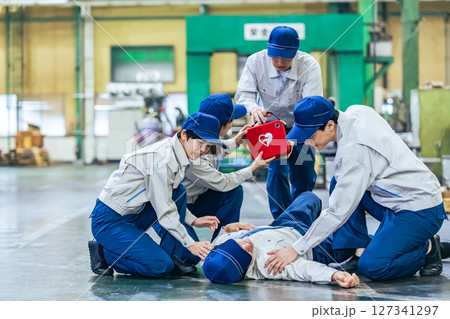 工場で倒れた作業員をAEDで救護するグループ 127341297