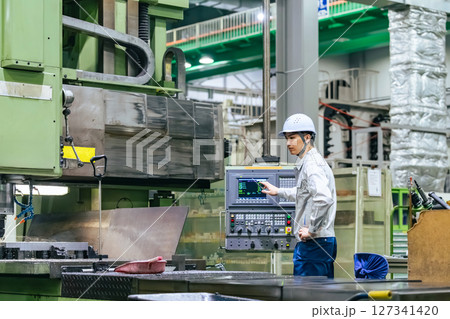 工場で操作盤で機械を操作する男性作業員 工場で操作盤で機械を操作する男性作業員 127341420
