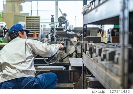 工場で工作機械を操作する作業員 127341426