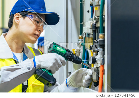 工場で工作機械のメンテナンスをする作業員 127341450