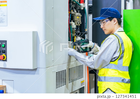 工場で工作機械のメンテナンスをする作業員 127341451