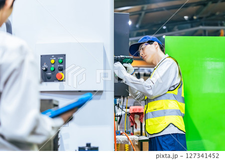 工場で工作機械のメンテナンスをする作業員 127341452