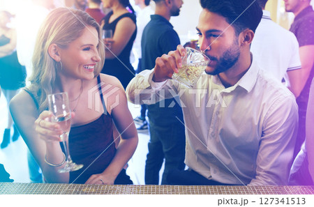 Party, man and woman talking and drinking on a date to celebrate new years eve with dancing. Dating, partying and a couple of friends chat while celebrating at the disco with alcohol drinks 127341513