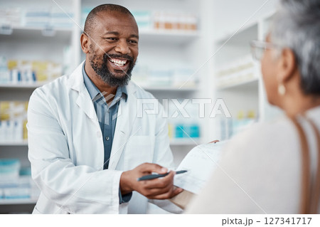 Pharmacy, medicine and pharmacist in discussion with a patient explaining her prescription. Healthcare, medical and African male chemist speaking to a woman at a pharmaceutical clinic or drug store. 127341717