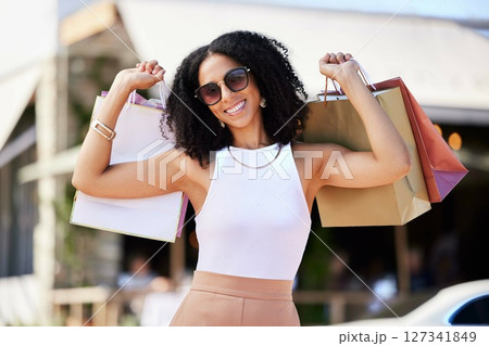 Fashion, shopping and retail with a black woman customer in the city with bags for consumerism or spending. Sale , market and street with a happy female consumer buying goods an an outdoor store 127341849