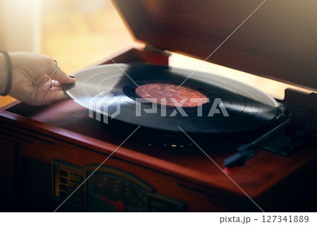 Record player, hand and woman playing music in home living room. Classic technology, retro and female putting vintage vinyl record in turntable or gramophone to play sound, audio or song in house. 127341889