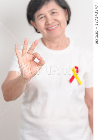 World hepatitis day awareness month, 28 July. elderly woman with Red and Yellow ribbon. Liver cancer, Jaundice, Cirrhosis, Failure, Enlarged, Hepatic Encephalopathy and Health concept 127343547