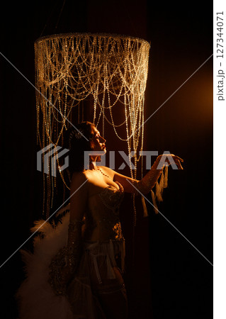 Circus-inspired retro burlesque dancer posing in golden corset with theatrical decor 127344071