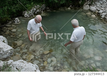 Two Elderly Men Wading in a Rocky, Green Stream 127344413