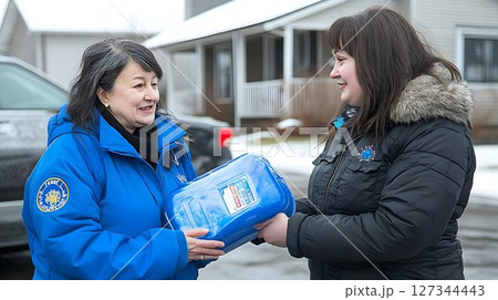 Winter Aid Exchange: Woman in Blue Jacket Hands Container to Ano 127344443