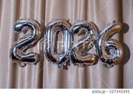 Happy new year 2026 metallic balloons on atlas textile background. Greeting card silver foil balloons numbers Christmas holiday concept. Celebration party congratulation 127345345