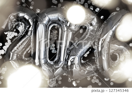 Holiday bokeh garland Happy new year 2026 metallic balloons with confetti on dark black background. Greeting card silver foil balloons numbers Christmas holiday concept. Celebration party 127345346