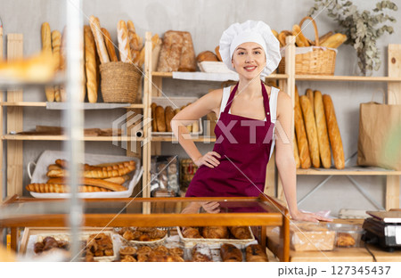 Portrait of smiling female baker in uniform in bakery Portrait of smiling female baker in uniform in bakery 127345437