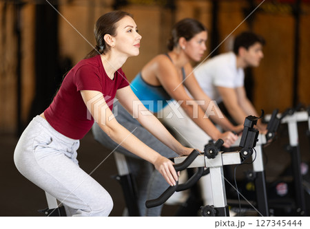 Woman exercising on an exercise bike Woman exercising on an exercise bike 127345444