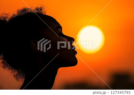 Silhouette of a Woman in Profile Against a Fiery Sunset Sky 127345793