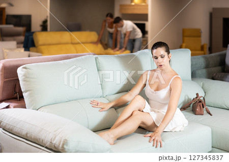 Young woman choosing convenient sofa in furniture shop 127345837
