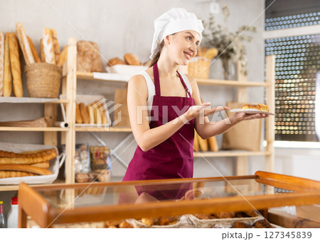 Young female seller with cake in bakery 127345839