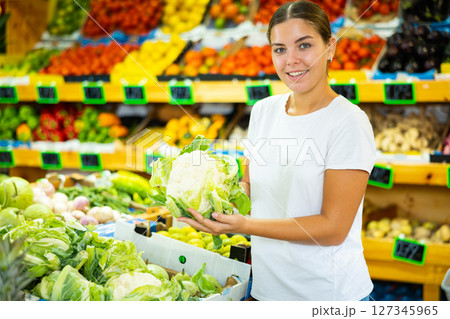 Cheerful young girl client buying cauliflower at market Cheerful young girl client buying cauliflower at market 127345965