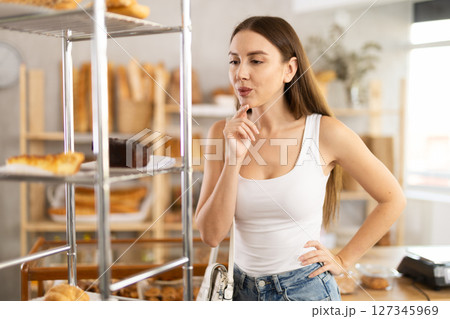 Satisfied female customer holding sweet pie in bakery interior 127345969