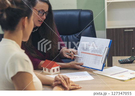 Team diversity women selling house real estate agent at office desk. Women working home insurance mortgage sale apartment realtor dealership. Businesswoman real estate house agent discuss to customer 127347055