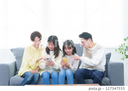 リビングでスマートフォンを使う親子 リビングでスマートフォンを使う親子 127347555