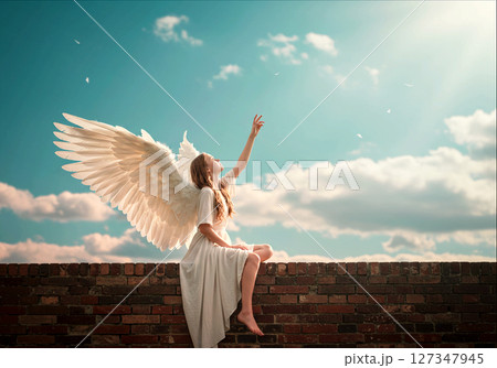空に手を伸ばす天使。光に包まれた祈り 127347945