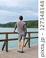 Young man standing near lake, view from back. Recreation in nature concept Young man standing near lake, view from back. Recreation in nature concept 127348148